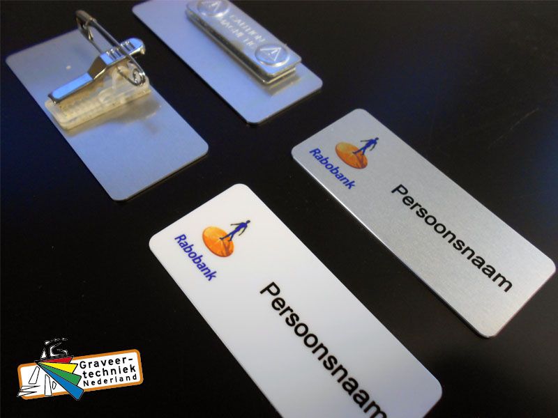 Metalen naambadge, in dit geval bv logo Rabobank links en persoonsnaam rechts
